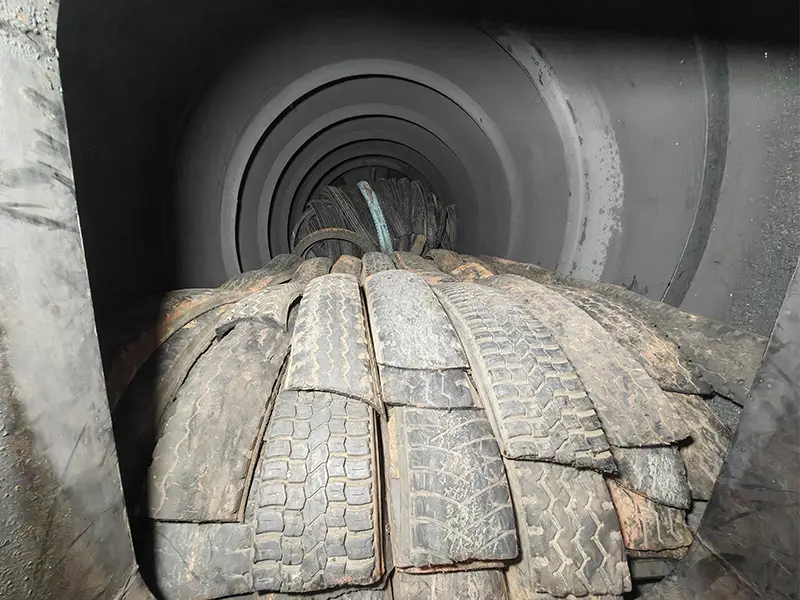 Shredded waste tire strips loaded into pyrolysis reactor.